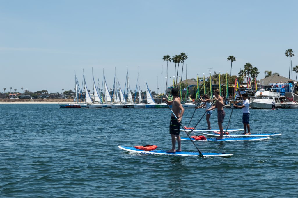 Friends paddling stand-up paddleboards together on Mission Bay