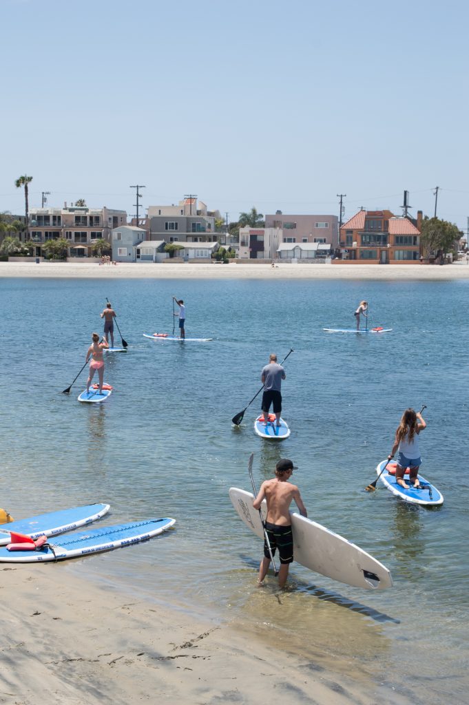 A group of guests paddleboarding together from the Mission Bay Sportcenter waterfront