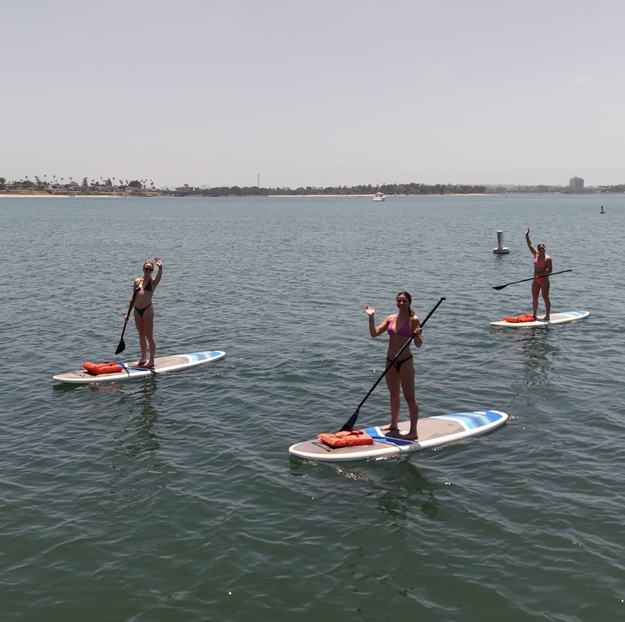 Paddleboarders waving on Mission Bay during a group water activity