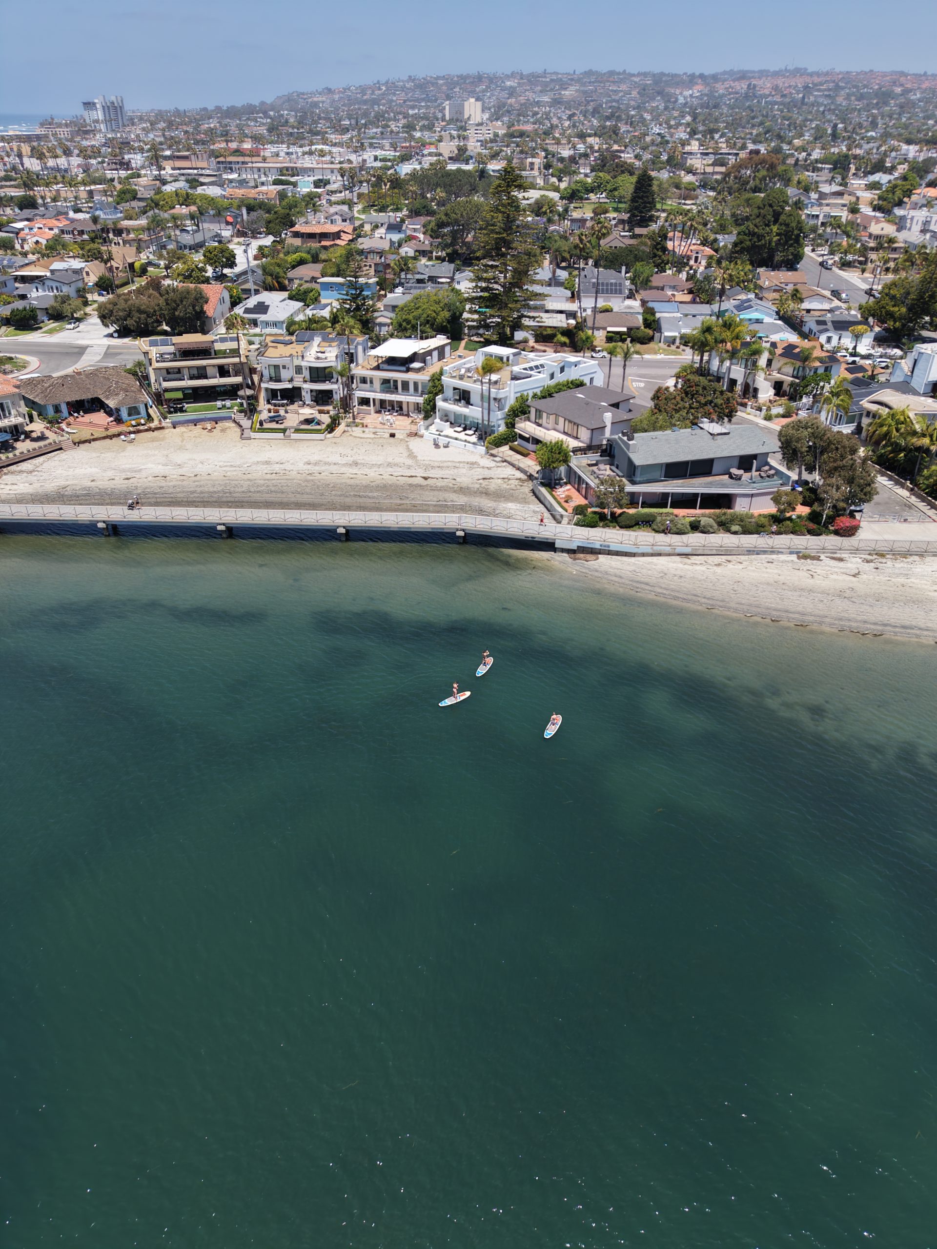 High aerial view over Mission Bay water, shoreline patterns, and central waterfront activity