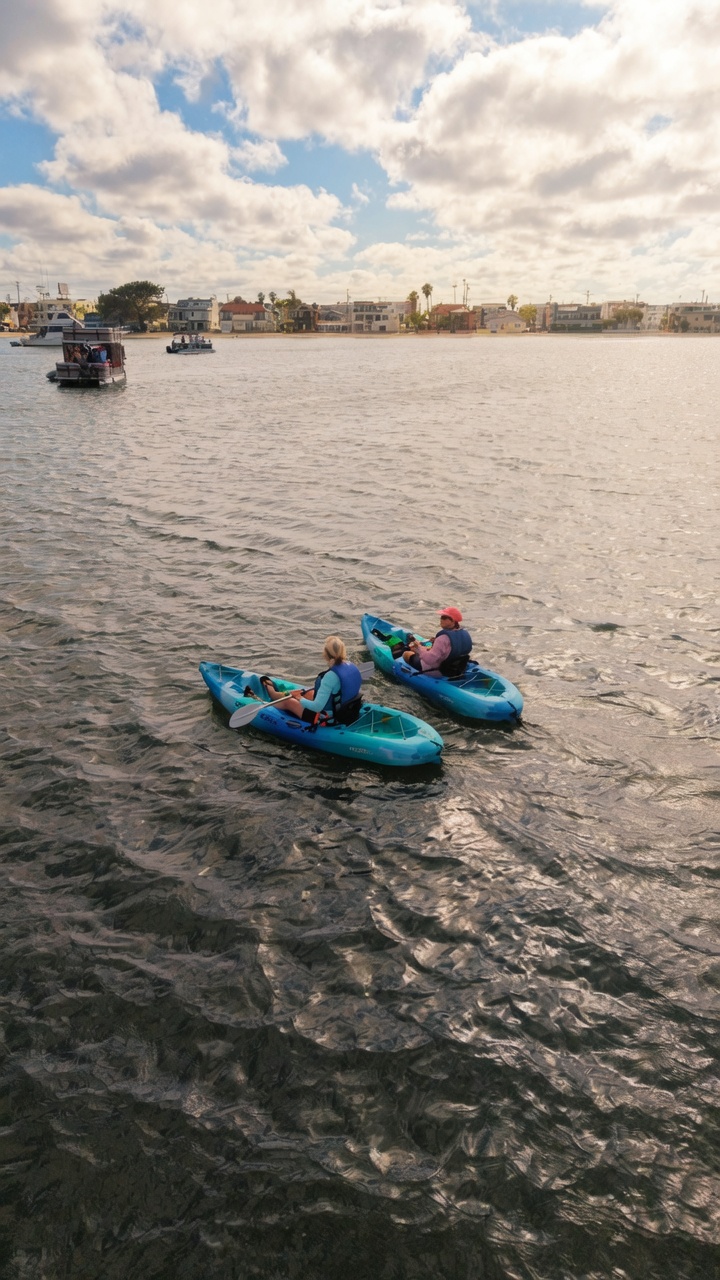 Two guests paddling separate single kayaks on Mission Bay